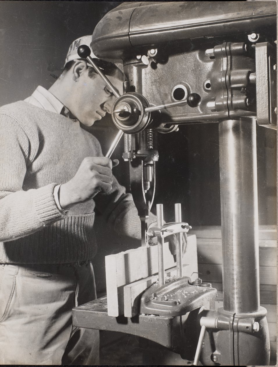 [Un homme utilise une machine pour percer des trous dans deux blocs de bois]. - Arnold Eagle