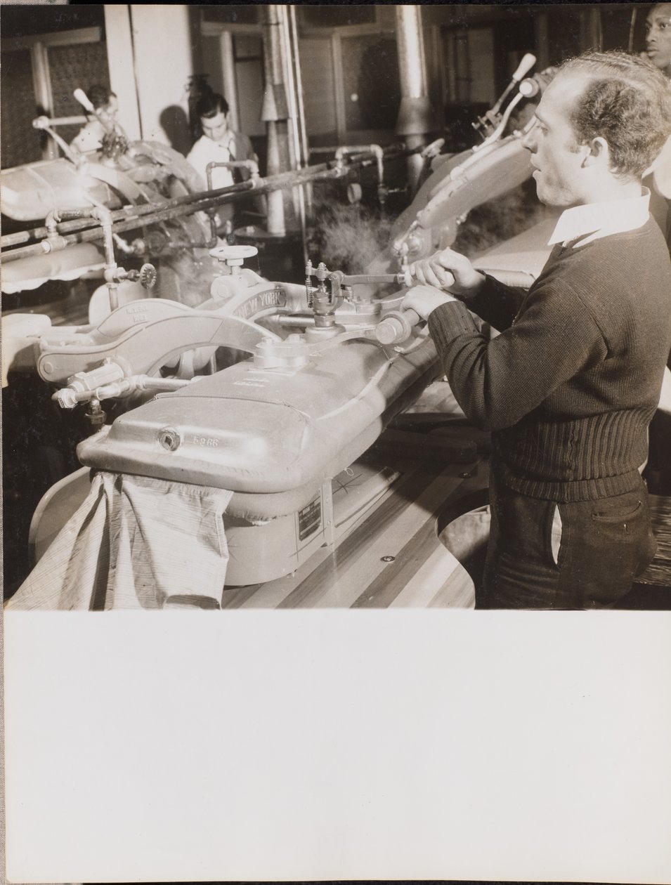 [Un homme utilise une machine pour presser des robes]. - Arnold Eagle