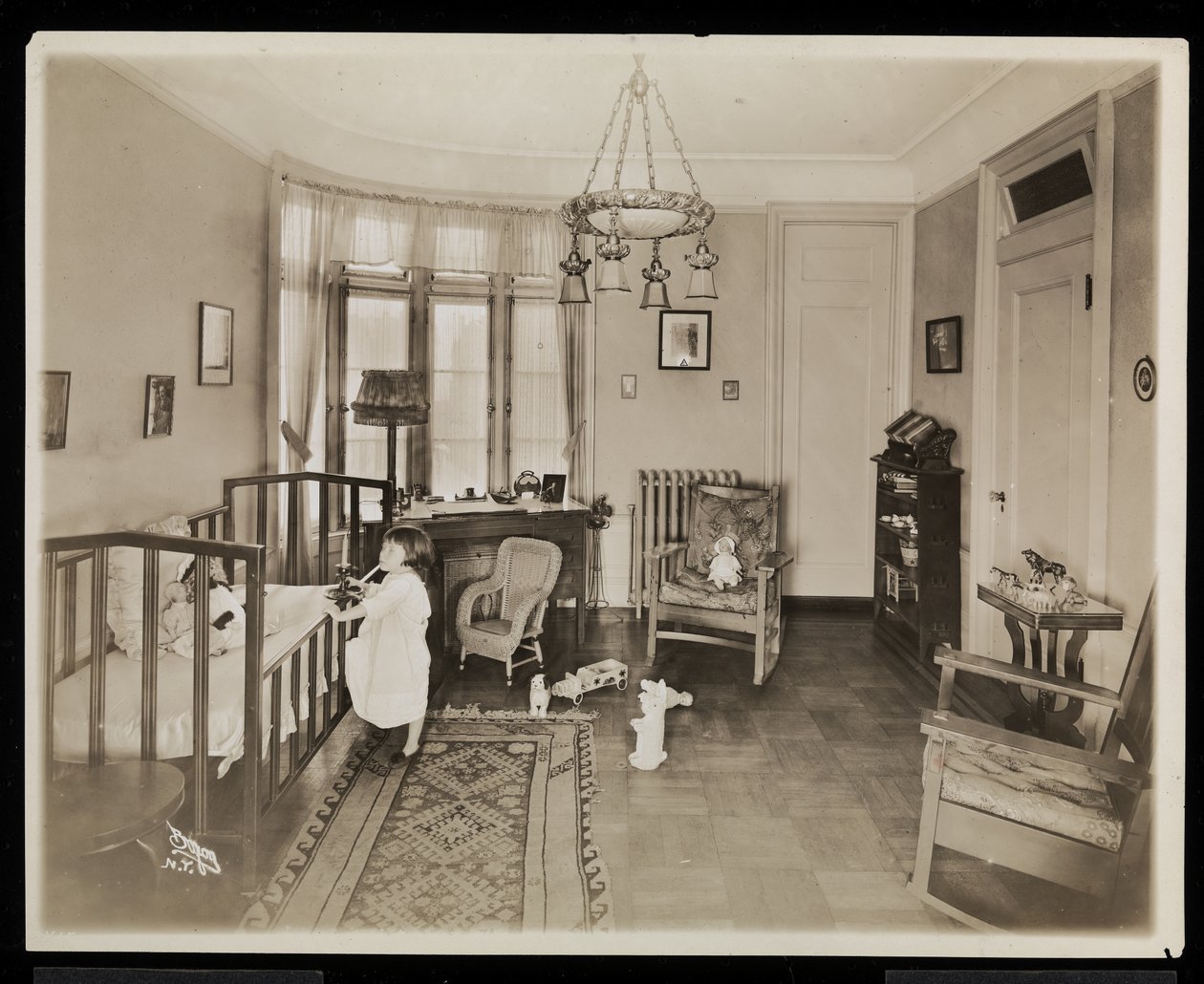 Une fille tenant une bougie, grimpant dans un berceau, dans une chambre de la résidence A.C. Cronin, 1915-16 - Byron Company