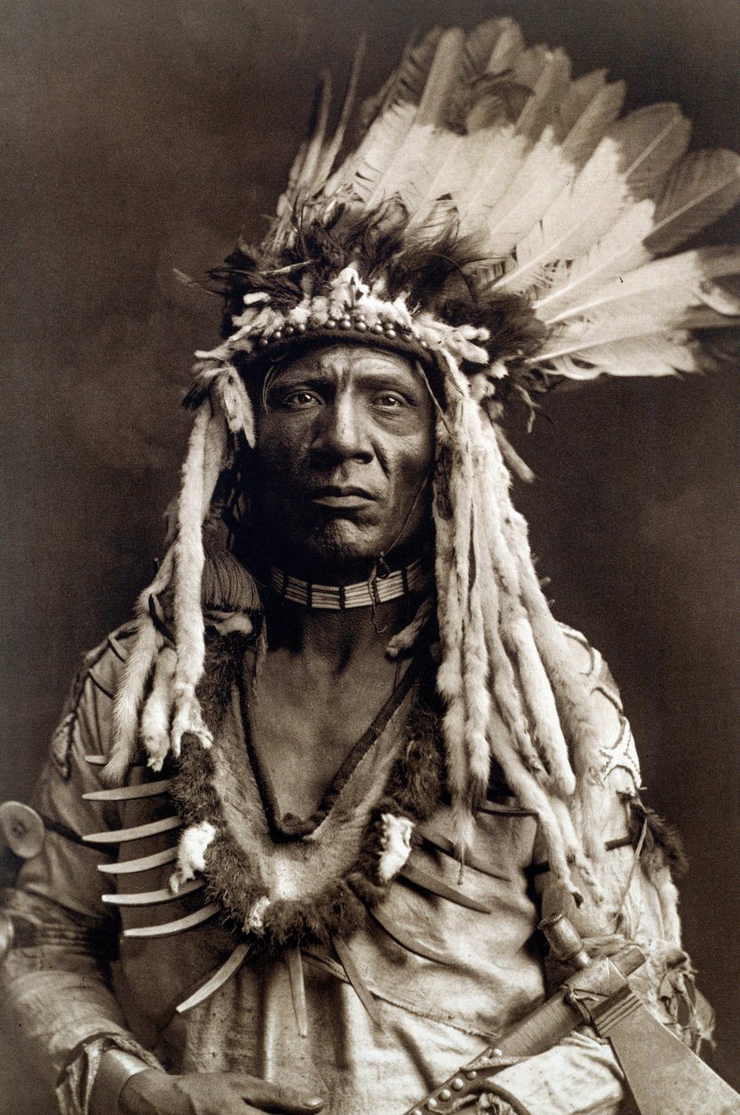 Queue de belette (Apohsuyis). Portrait du chef indien de la tribu Piegan portant la célèbre coiffe en plumes d
