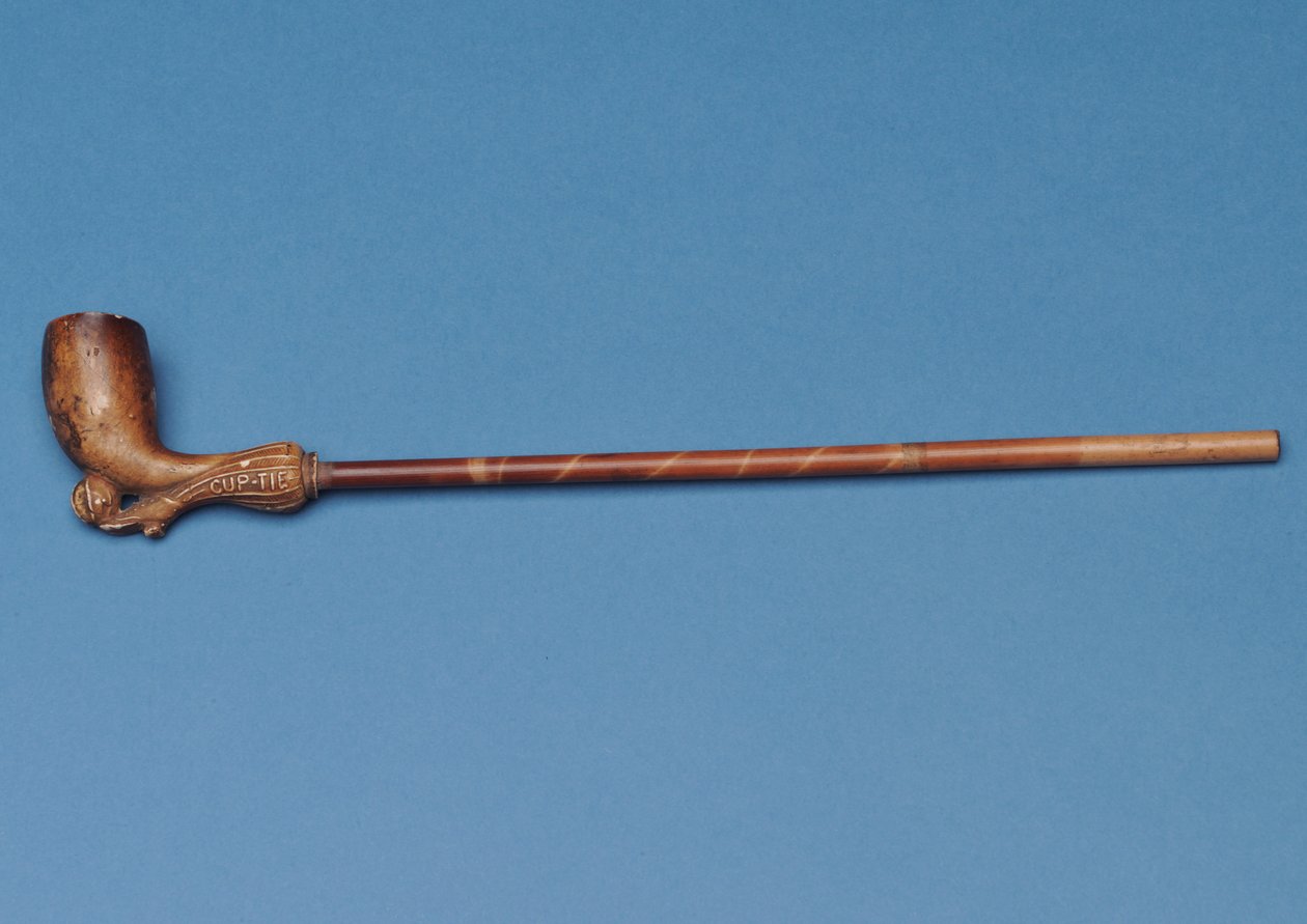 Pipe avec tige en bambou et botte sculptée frappant un ballon en dessous - English School