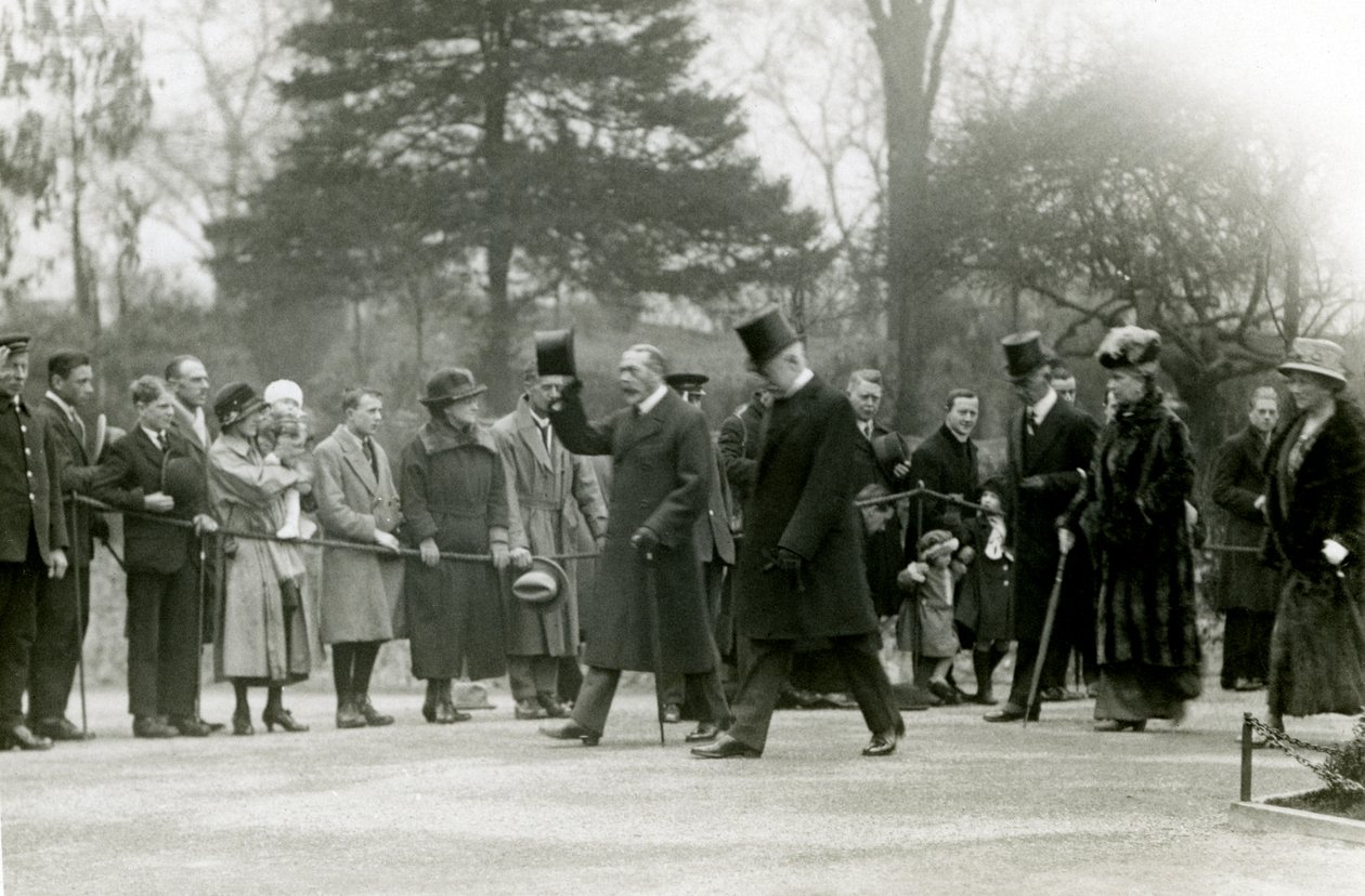 Le roi George V, levant son chapeau à la foule devant son entourage, lors d