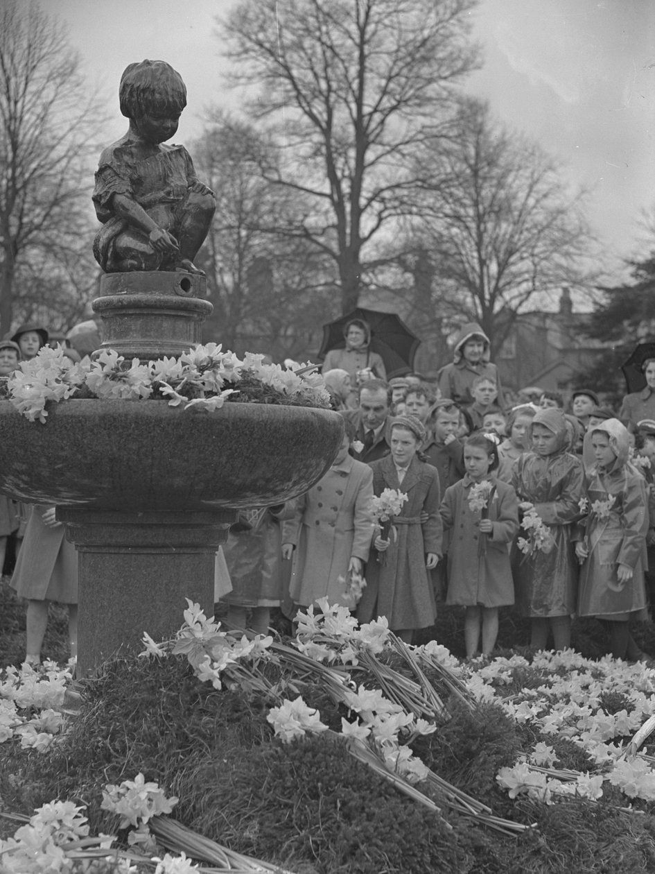 Enfants plaçant des bouquets de jonquilles sur une fontaine surmontée d
