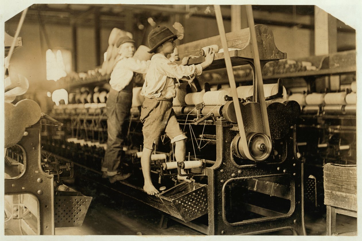 Petits garçons grimpant sur un cadre de filature pour réparer des fils cassés et remplacer des bobines vides à Bibb Mill, Macon, Géorgie, 1909 - Lewis Wickes Hine