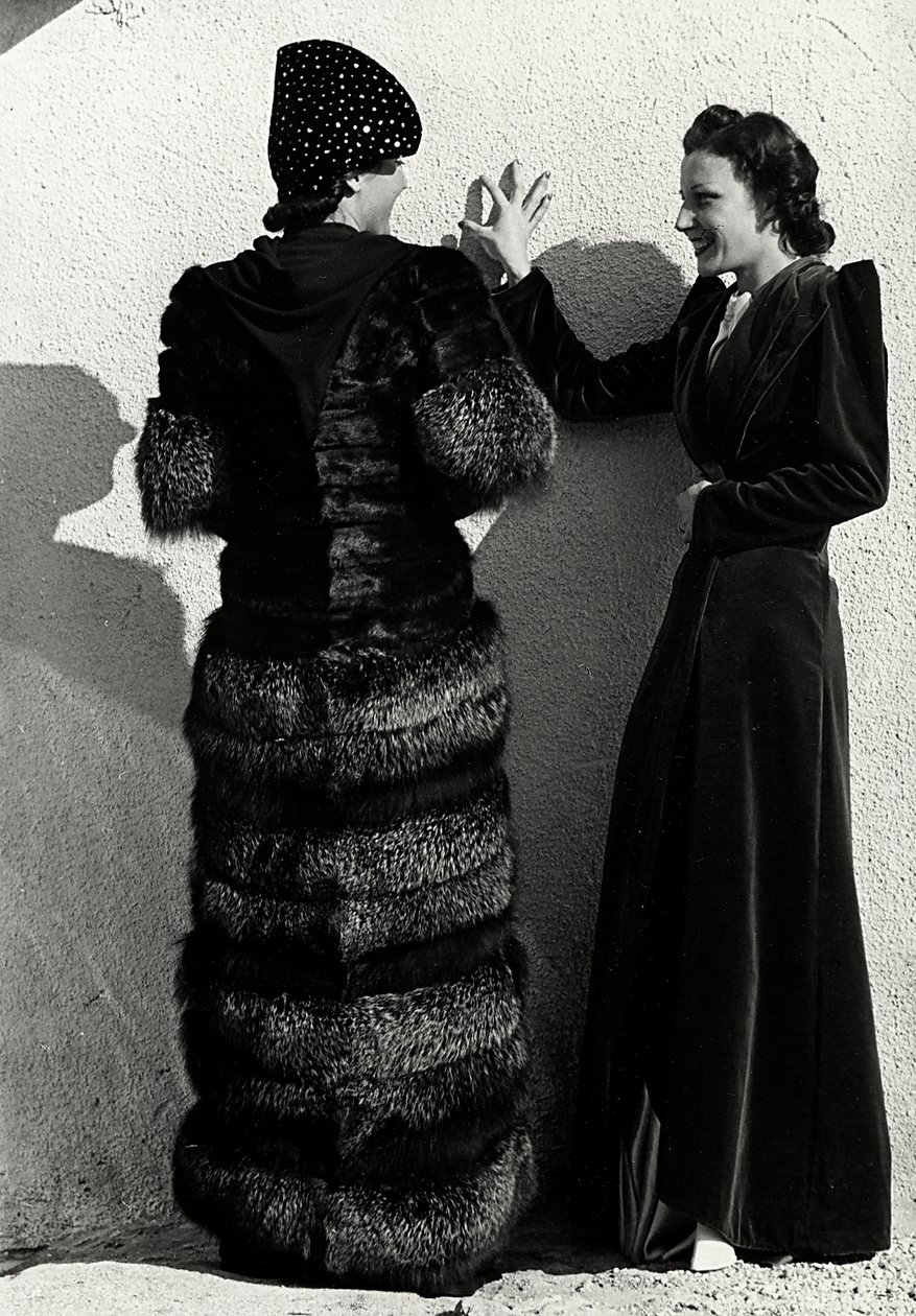 Deux mannequins présentent des créations de la maison de couture italienne "Dragoni". Un mannequin vu de dos porte un manteau en renard argenté. L