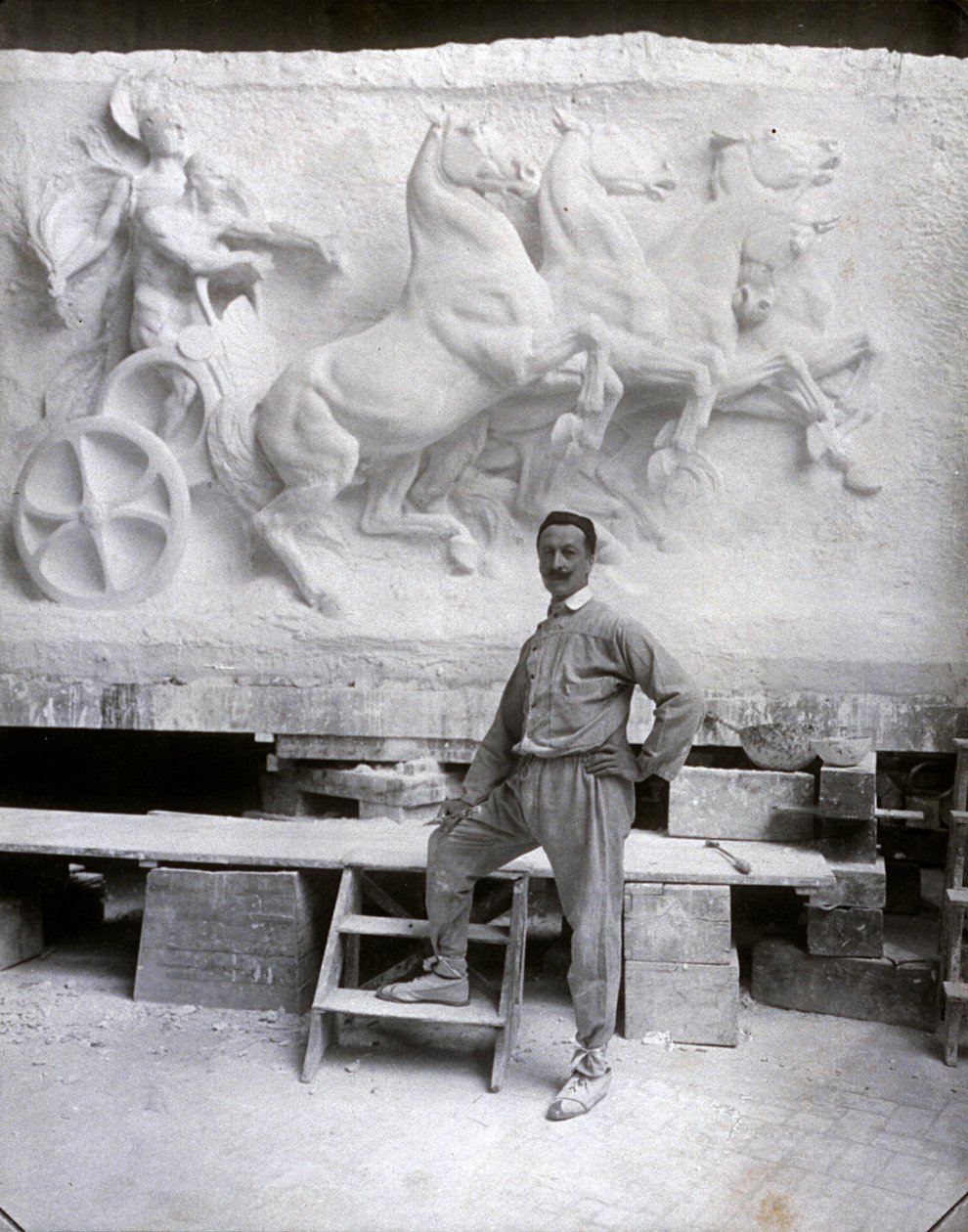 Portrait en pied du célèbre sculpteur Pietro Canonica. Il pose dans son atelier devant un haut-relief en marbre sur lequel il travaille - Mario Nunes Vais