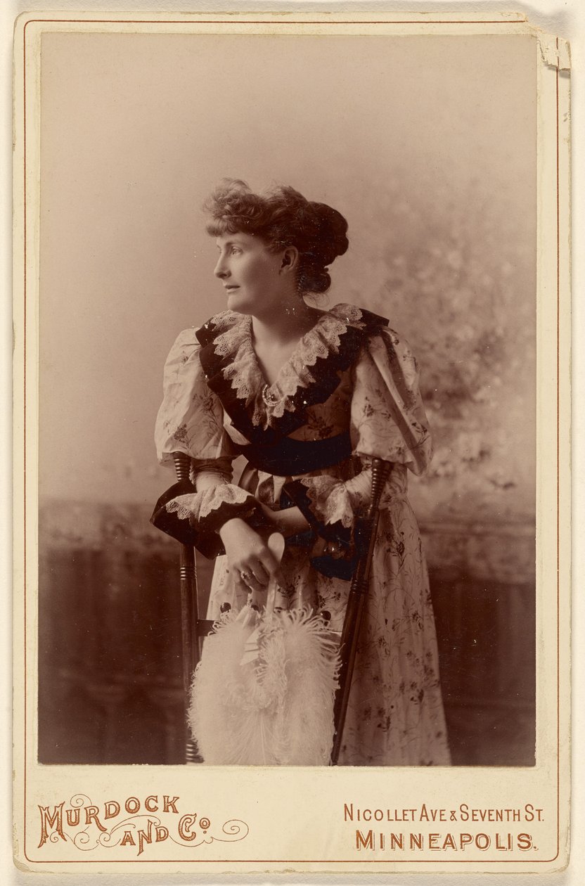 [Femme non identifiée de profil, appuyée sur une chaise, tenant un éventail de plumes]. - Murdock and Company
