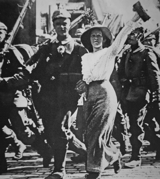 Les troupes allemandes de la Première Guerre mondiale marchant vers la guerre, leurs tuniques et fusils ornés de fleurs de la foule en liesse - Photographer German