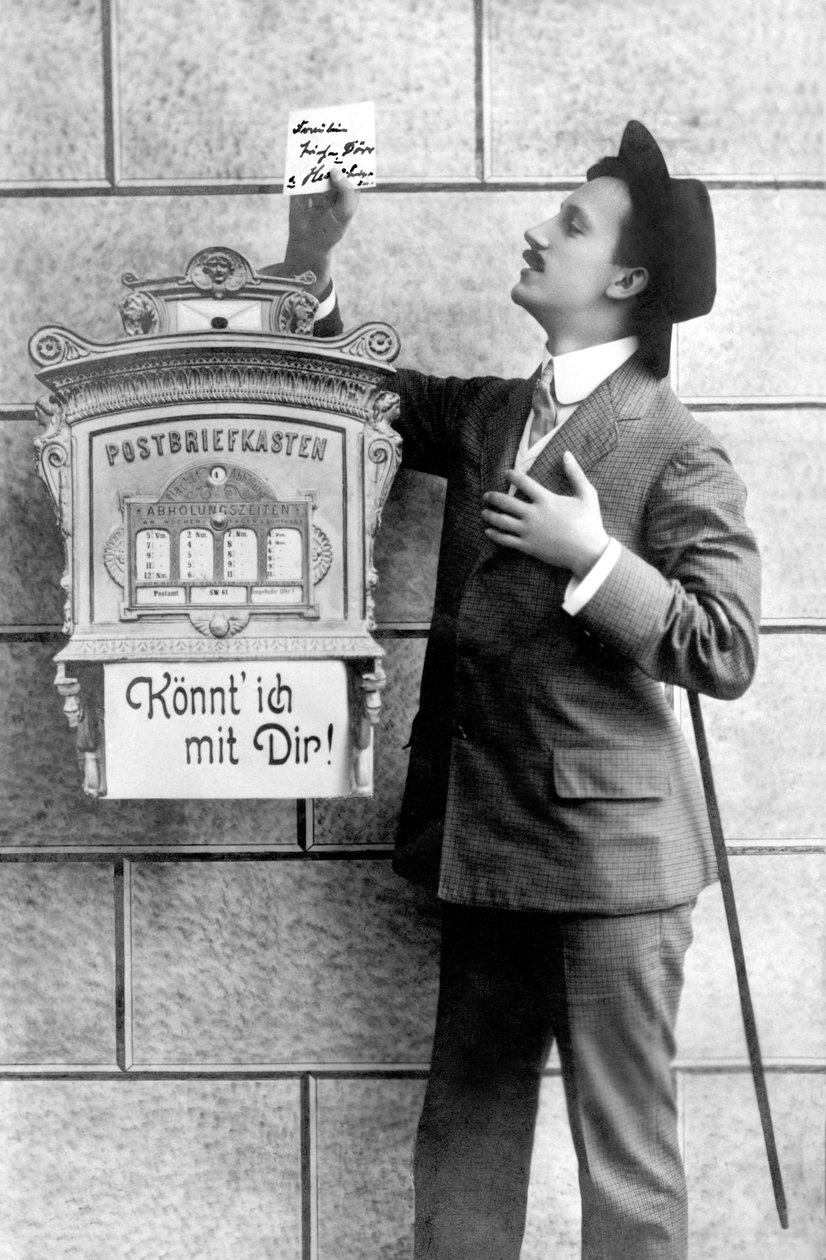 Un homme élégant en costume, chapeau et canne, poste une note dans une boîte aux lettres. Allemagne vers 1920 Photographie historique, homme à côté d
