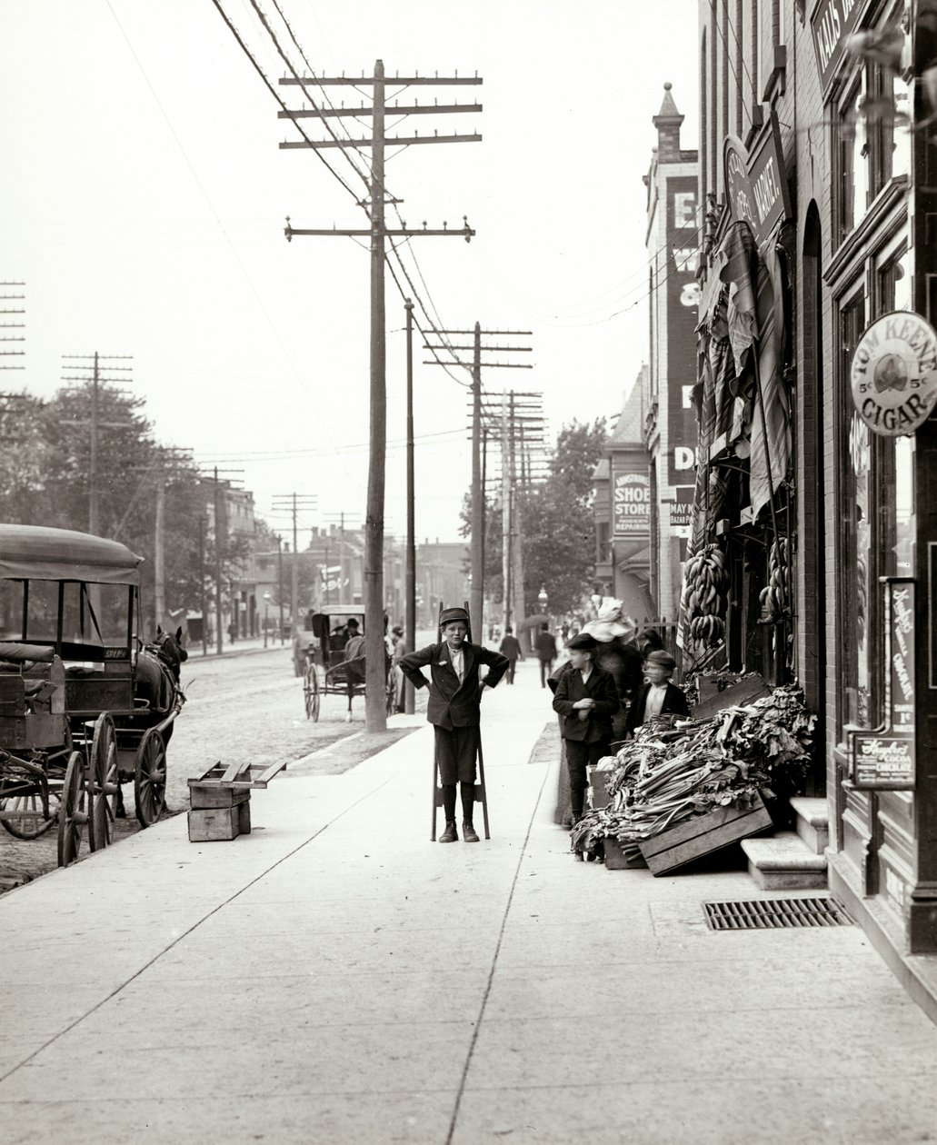 Un garçon avec des échasses devant le marché F.J. Voepel au 4874 Easton Avenue, au coin sud-est d