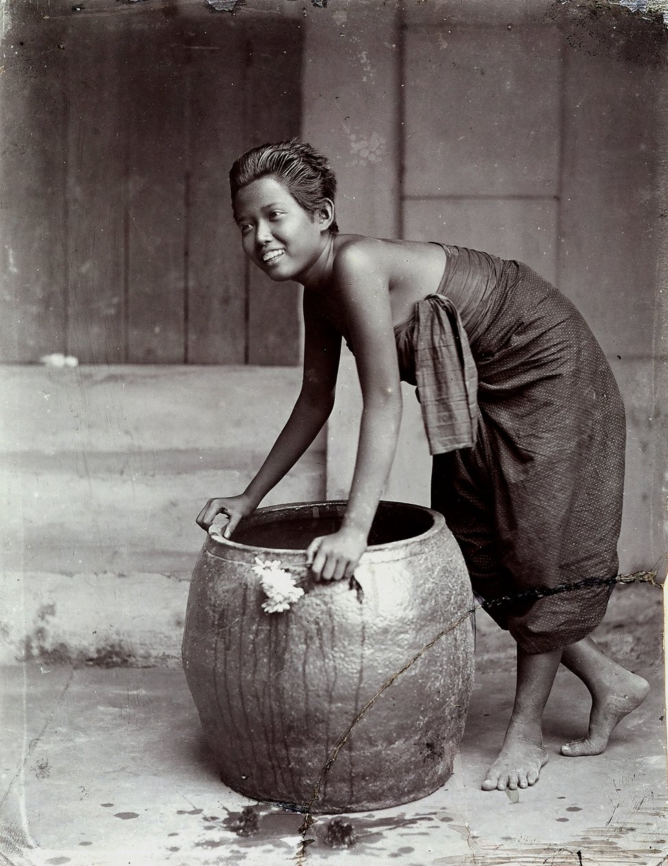 Jeune femme thaïlandaise souriante, poussant un grand conteneur - Unknown photographer