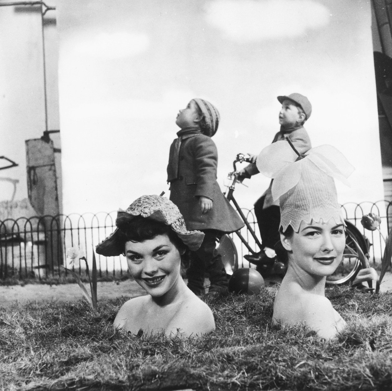Femmes portant de chapeaux en forme de fleur, dont le corps dissimule dans le sol donne l