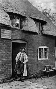 Un homme fumant une pipe devant un magasin, Worcestershire - A. W. Cutler
