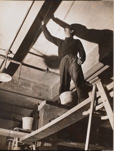 [Un homme debout sur un échafaudage en bois peint un plafond]. - Arnold Eagle
