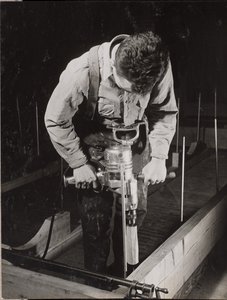 [Un homme utilise une machine portative pour travailler un morceau de bois]. - Arnold Eagle