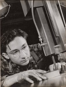 [Un homme portant des lunettes travaille intensément avec un dossier industriel].