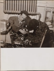 [Deux hommes travaillent sur une machine à l