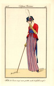 Femme en robe de lin rayée et gilet en soie côtelée souple, chapeau avec cocarde. Elle écrit amour avec sa canne dans le sable