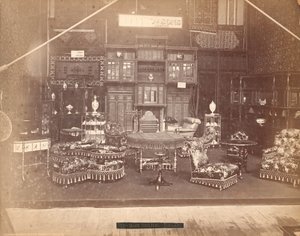 Exposition de S. Howard & Sons - Bâtiment principal, collection de meubles, y compris des chaises rembourrées, des tables, une cheminée, des armoires et des étagères. Sur les murs, des tapis, et sur les tables et étagères, des vases