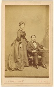 [Couple non identifié : femme debout, homme à la barbe de Vandyke assis].
