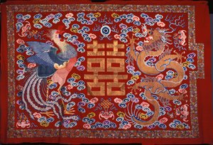 Un pendentif chinois en laine rouge avec un caractère central en fil doré flanqué d