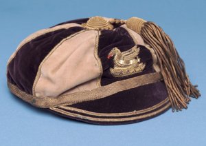 Casquette de football segmentée bleu et blanc avec badge dragon en métal et pompon doré