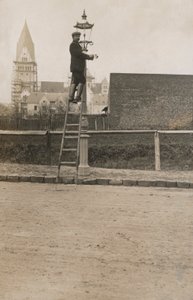 Homme sur une échelle réparant un lampadaire