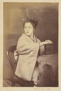 [Femme japonaise assise tenant un album de cartes-de-visite à une table].