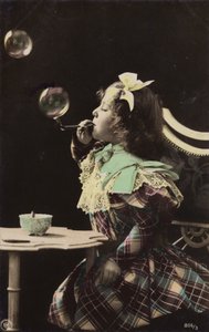 Une petite fille soufflant des bulles avec une pipe