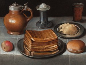 Gaufres et beurre sur des assiettes en étain avec une pomme, un rouleau, une cruche, du sel debout et un verre de bière avec des prunts sur une table couverte de tissu