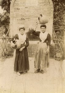 Deux jeunes femmes portant des vêtements traditionnels et des jarres en terre cuite près d