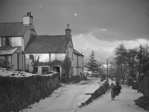 Femme portant une branche sur la route près de Borwick Fold Farm à Hawkshead dans la neige