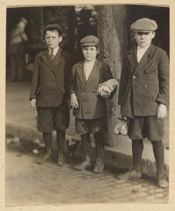 [Trois garçons dans la rue de la ville en culottes et bonnets]