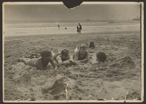 [Enfants allongés dans le sable à la plage]