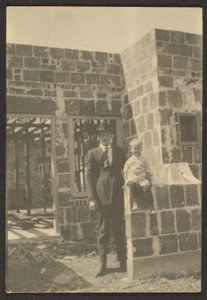 [Homme debout avec un enfant dans une maison en construction]