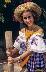 Femme en chapeau de paille du Panama broyant avec un mortier et un pilon traditionnels.