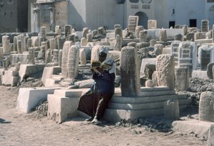 Un homme yéménite récite le Coran dans un cimetière avec des tombes à Sayun, Hadramawt, Sud-Yémen.