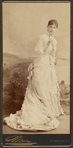 [Femme non identifiée portant une longue et élégante robe blanche, debout]