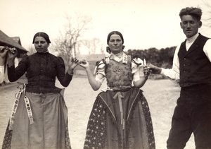 Deux dames et un homme, en costumes traditionnels hongrois, se tenant par la main dans une danse, tenant des bougies - Rudolf Balogh