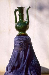 Femme à Kaboul isolée de la vue par un chadri en soie alias chador portant une cruche