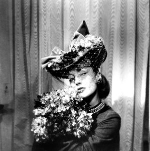 Femme portant un chapeau avec un voile, tenant un bouquet de fleurs, Paris, 1943