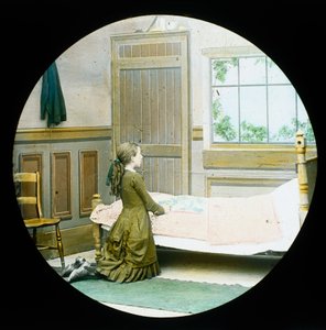 Une fille agenouillée en prière à son chevet, lanterne magique, vers 1890