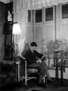 Un adolescent assis dans un intérieur bourgeois lit un livre, porte un short et des chaussettes hautes. 1915. Photo historique, femme lisant, vers 1915.
