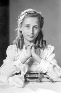 Jeune fille chrétienne avec les mains jointes en position de prière avec bible, chapelet et bougie (photo de communion). Photographie vers 1932