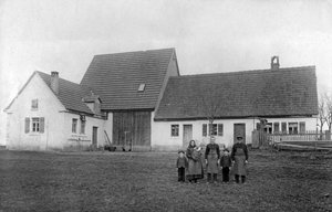 Famille de fermiers posant devant la ferme.