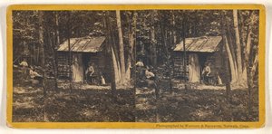 [La famille pose devant sa cabane en rondins dans les bois].