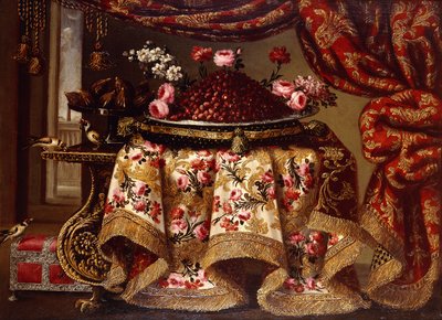 Un plat de fraises avec des fleurs sur un oreiller et une coupe de figues sur une table drapée d