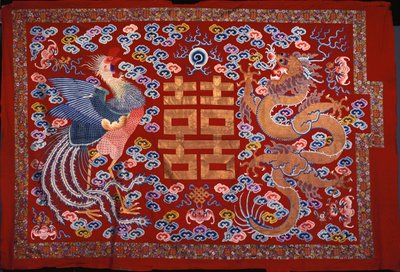 Un pendentif chinois en laine rouge avec un caractère central en fil doré flanqué d
