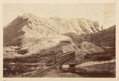 Vues sur le chemin de fer du Pacifique, de la voie ferrée traversant une rivière sur un pont en treillis, avec des montagnes au-delà - English Photographer