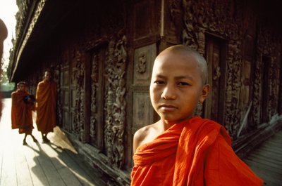 Un jeune novice moine devant des panneaux de teck sculptés. Monastère Shwenandaw, Mandalay, Birmanie - James L Stanfield